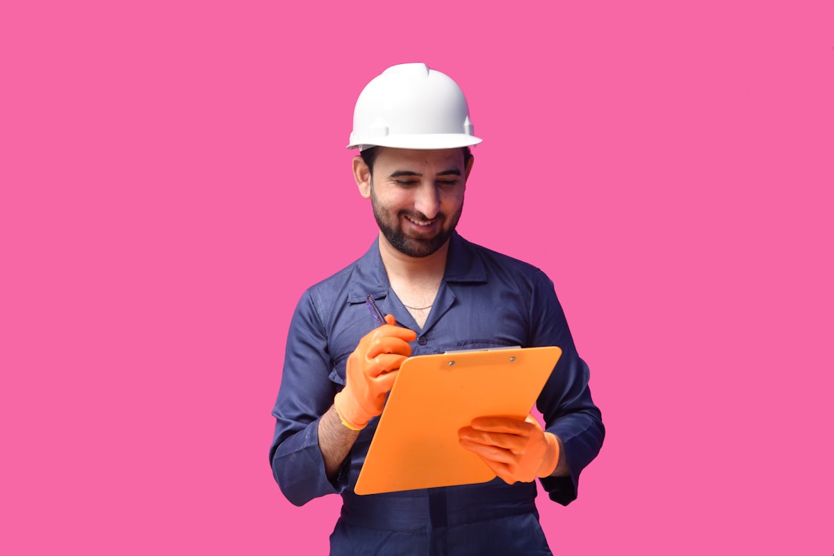 A man wearing a hard hat and holding a yellow folder