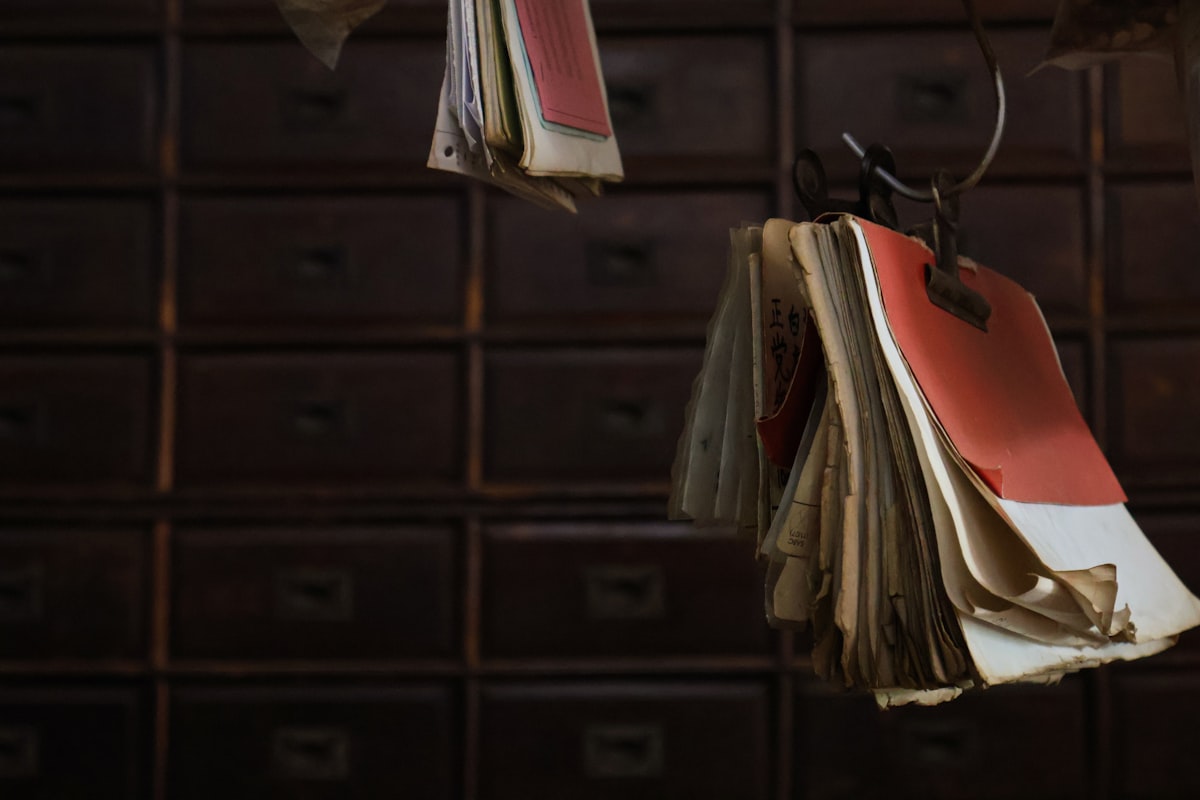 Old books hang in front of wooden drawers.