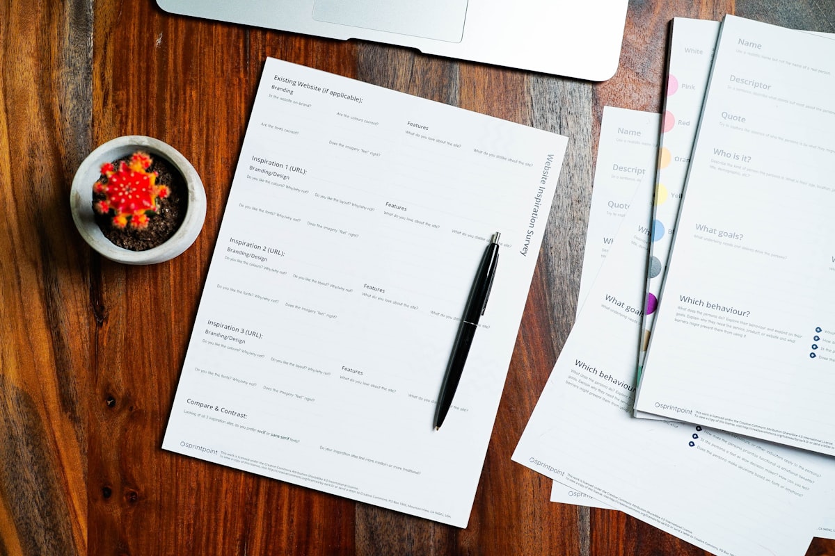 A wooden table topped with papers and a pen