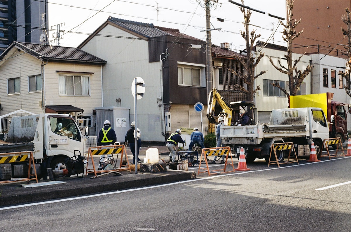 Construction workers on a city street with vehicles.