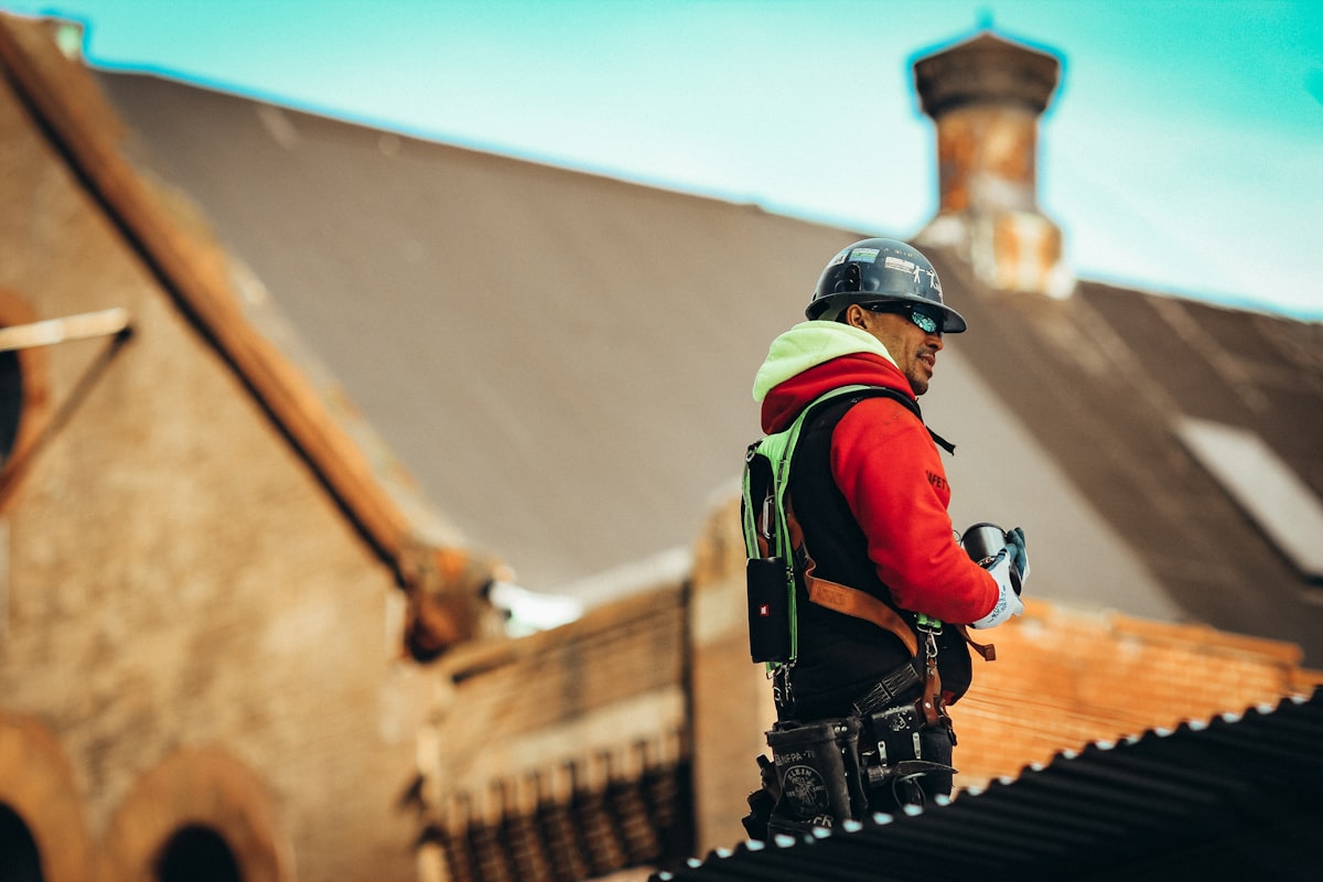 Man in black helmet and red and black jacket standing on brown concrete stairs during daytime