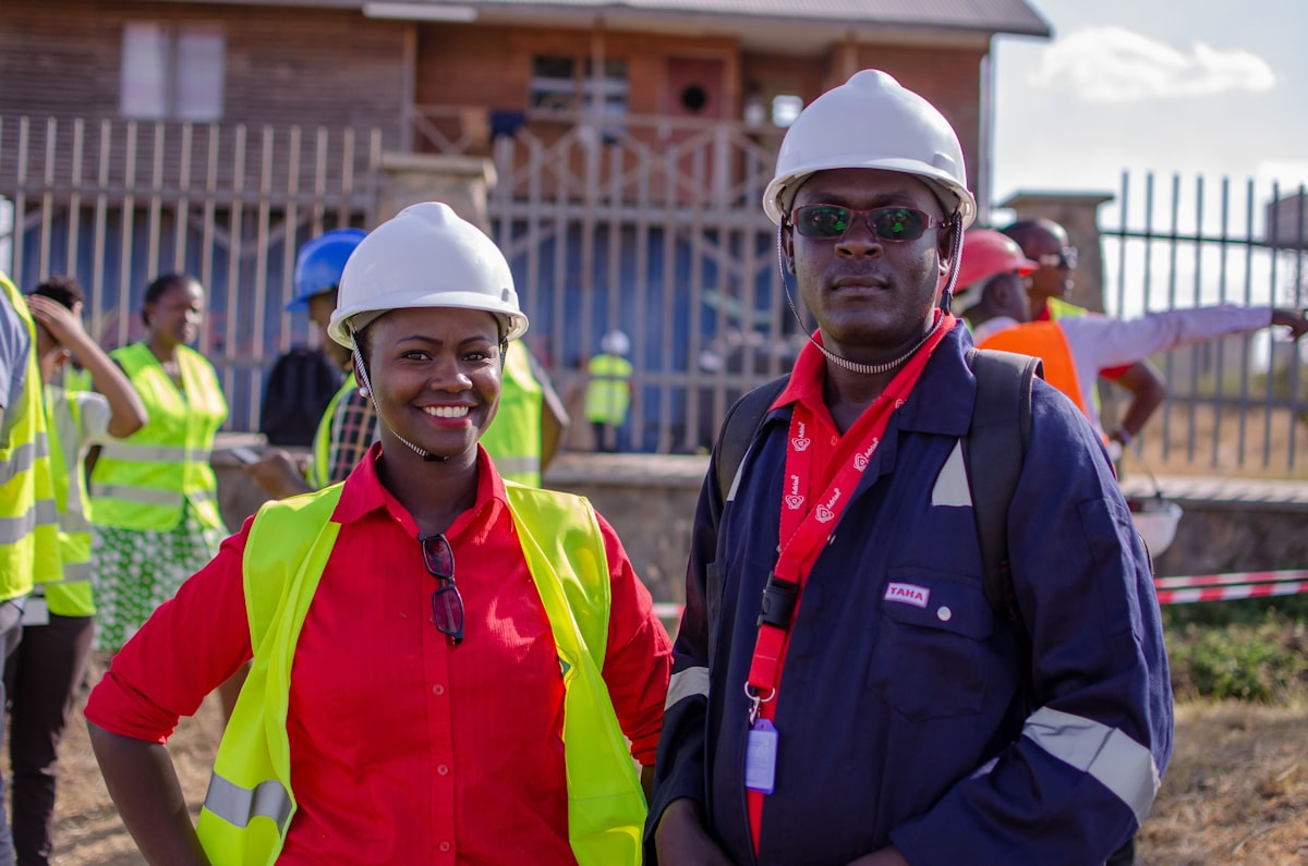 Man in blue jacket wearing white cap and red and green vest