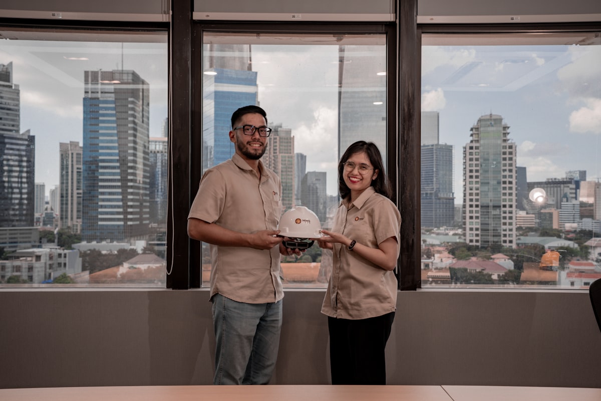 Two people holding a hard hat with city view
